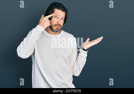 Uomo caucasico di mezza età che indossa abiti casual confuso e infastidito con la palma aperta che mostra lo spazio di copia e punta il dito alla fronte. Pensateci Foto Stock