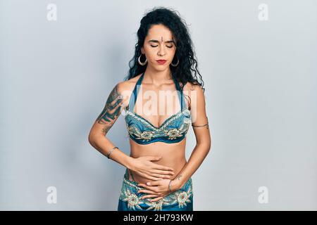 Giovane donna che indossa bindi e tradizionali abiti da danza del ventre con mano sullo stomaco perché indigestione, malattia dolorosa sensazione di malessere. Mal di concetto. Foto Stock