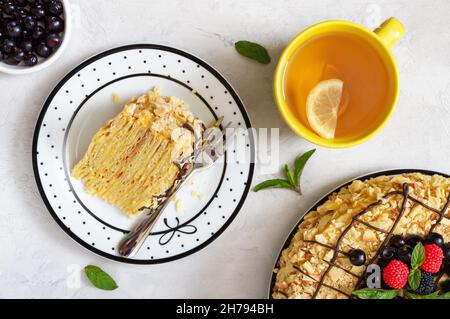 Un pezzo di torta di pasta Napoleone su un piatto con una tazza di tè. Vista dall'alto, piatto. Foto Stock