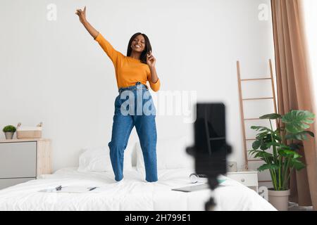 African Woman Making Video su cellulare Dancing su Bed Indoor Foto Stock