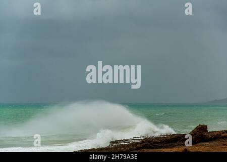 arrabbiato colore verde turchese massiccio arricciamento di un'onda come il cilindro rotola lungo l'oceano. Foto Stock