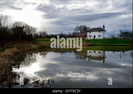 Il Lock Keeper's Cottage si riflette nella sterlina superiore, Foxton Locks, Grand Union Canal, Leicestershire, Inghilterra. Foto Stock