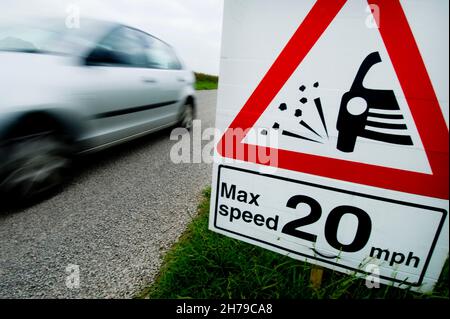 L'auto supera una velocità massima temporanea di 20 mph e segnala la presenza di schegge allentate su una strada di campagna B, Leicestershire, Inghilterra, Regno Unito. Foto Stock