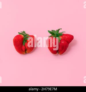 Vista dall'alto delle fragole deformate su sfondo rosa morbido. Concetto di movimento alimentare brutto Foto Stock