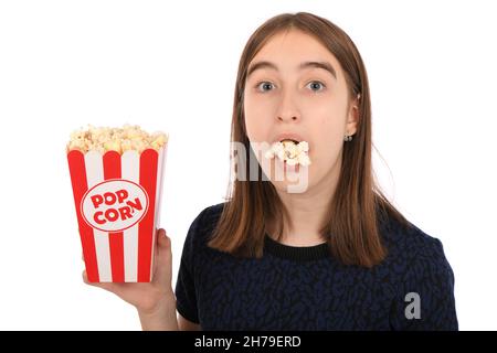 Ragazza adolescente che mangia popcorn, in piedi su bianco. Foto ad alta risoluzione. Foto Stock