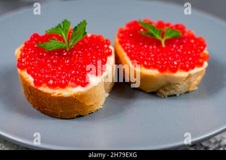 Sandwich con caviale rosso primo piano su un piatto grigio. Cibo festivo. Foto Stock