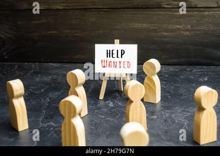 Un uomo con un segno voluto Aiuto fa appello alla folla circa l'assunzione. Chiedere aiuto, volontariato. Ricerca e reclutamento di nuovi dipendenti per lavoro. Noleggio s Foto Stock