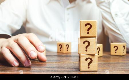 L'uomo è nel pensiero e si blocca con le domande. Ponderare il problema, raccogliendo tutti i fatti. Prendere la decisione giusta. Ragionamento, pesatura dei risultati e. Foto Stock