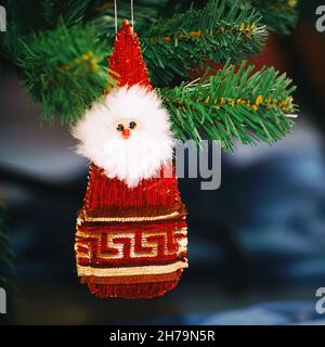Un giocattolo o bambola di Babbo Natale è appeso sull'albero di Natale accanto ai regali Foto Stock