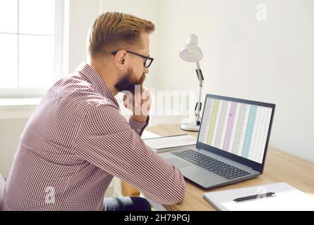 Un serio contabile finanziario che guarda il foglio di calcolo sullo schermo del notebook e pensa Foto Stock