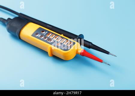 Primo piano dell'indicatore di tensione a due poli su sfondo blu. Test e verifica delle reti elettriche Foto Stock