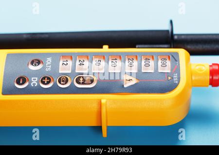 Indicatore di tensione giallo su sfondo blu. Spazio libero Test e verifica delle reti elettriche Foto Stock