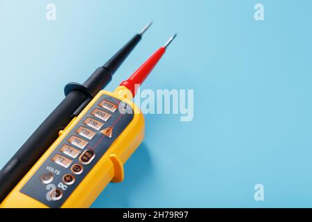 Indicatore di tensione giallo su sfondo blu. Spazio libero Test e verifica delle reti elettriche Foto Stock