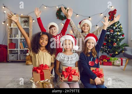 Sorridendo i bambini con regali che guardano la macchina fotografica durante la festa di Natale a casa Foto Stock