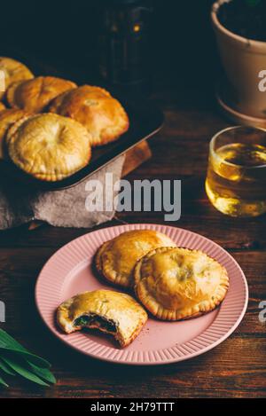 Dolci al forno ripieni di Chives e funghi sul piatto con tazza di tè. Un Pie con Bite ne ha tesi fuori Foto Stock