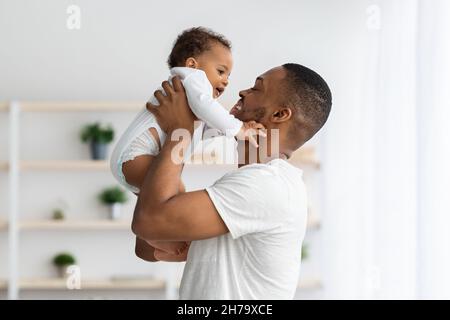 Concetto di Father's Day. Amando giovane papà nero sollevare cute bambino infantile Foto Stock