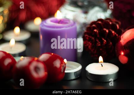 Candele illuminate con ornamenti natalizi come Baubles Cone Cone Cherries Pine e pelliccia rossa in background. Tema per buon Natale e Felice anno nuovo Foto Stock