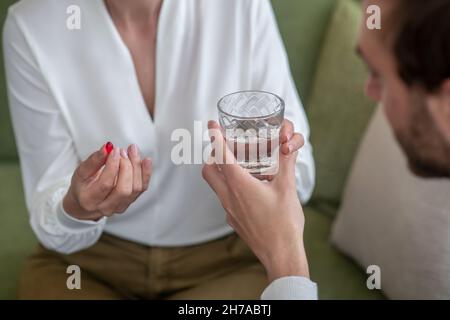 Figlio che dà alla madre un bicchiere d'acqua mentre lei si sente malata Foto Stock