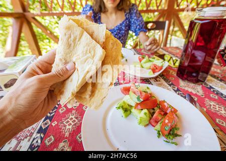 Una cena abbondante in un ristorante armeno. Lavash tradizionale del pane in mano. Foto Stock