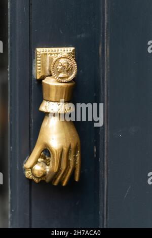 Mano d'oro che tiene una porta manopola a una porta bussare a Londra Foto Stock