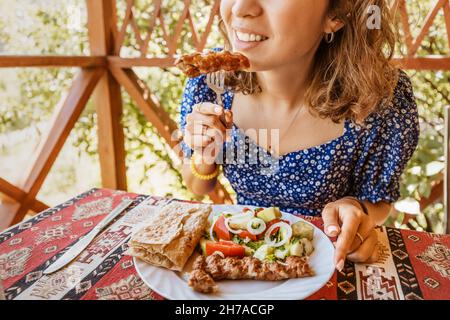 Una donna mangia un piatto armeno Lula Kebab con lavash in un caffè Foto Stock
