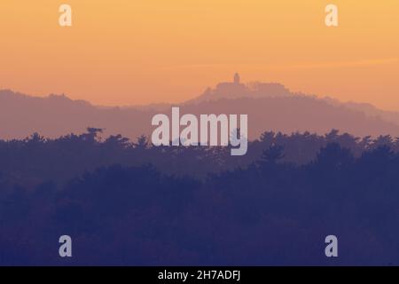 Bella vista sulle cime degli alberi a strati e la Chiesa Monrupino vicino Trieste in lontananza durante il crepuscolo. Foto di Monrupino, Italia Foto Stock