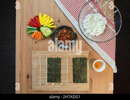 Sushi Rolling - stuoia di sushi di bambù, verdure a fette, riso appiccicoso e alghe nori Foto Stock