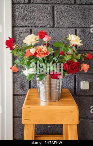 Un secchio con un bouquet di rose appena tagliato all'interno di un appartamento o di un ristorante Foto Stock