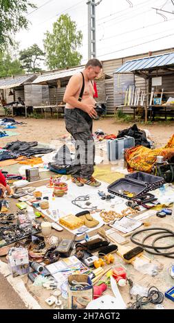 Il venditore vende articoli miscellanious venduti sul terreno in Udelka Udelnaya mercato delle pulci all'aperto, il più grande nella città di San Pietroburgo, Russia Foto Stock