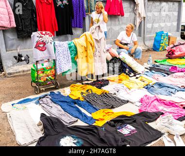 Donne che vendono abiti di seconda mano a terra nel mercato esterno delle pulci di Udelka Udelnaya, il più grande della città di San Pietroburgo, Russia Foto Stock