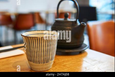Teiera asiatica e tazza su un tavolo da ristorante. Teiera nera Foto Stock