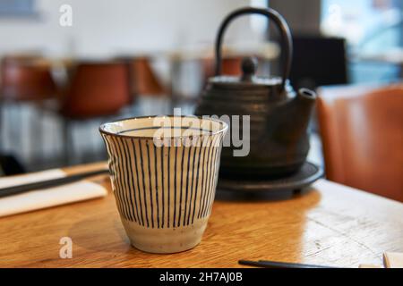 Teiera asiatica e tazza su un tavolo da ristorante. Teiera nera Foto Stock