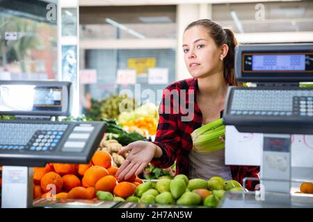 Giovane donna sorridente venditore che aiuta a scegliere le arance Foto Stock