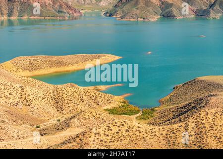 Vista su una gola di montagna con un serbatoio d'acqua di colore turchese brillante. Il fiume Azat in Armenia e montagne aride sullo sfondo. Foto Stock