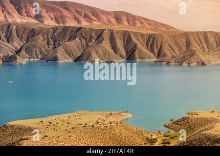 Vista su una gola di montagna con un serbatoio d'acqua di colore turchese brillante. Il fiume Azat in Armenia e montagne aride sullo sfondo. Foto Stock