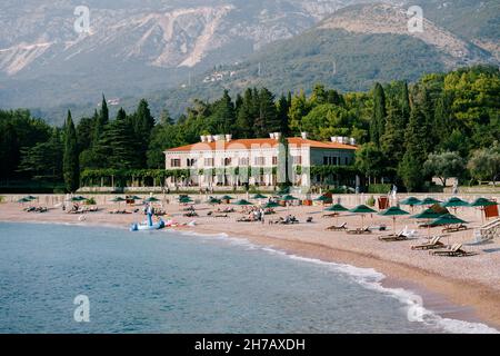 Sedie a sdraio e ombrelloni sulla spiaggia vicino a Villa Milocer. Montenegro Foto Stock