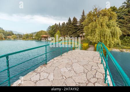 Un ponte pedonale su un pittoresco laghetto nel centro della tranquilla località turistica di Dilijan in Armenia. Foto Stock