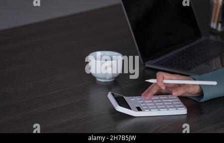 Primo piano bilancio di pianificazione della donna, utilizzando calcolatore e laptop, lettura di documenti, giovane donna controllo finanze, conteggio fatture o tasse, online Foto Stock