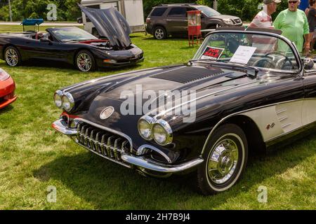 Un nero 1958 Chevrolet C1 Corvette convertibile pubblicizzato per la vendita contrasti con il C5 Corvette in un salone di auto a Fort Wayne, Indiana, USA. Foto Stock