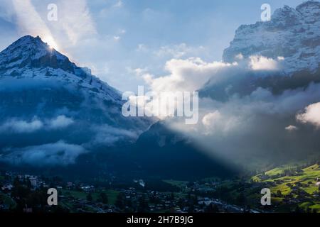 I raggi del sole della mattina presto scoppiarono sulla cima dello Shreckhorn e illuminarono le nuvole come si vede da Grindelwald, in Svizzera. Foto Stock