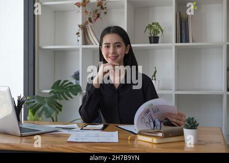 Ritratto di sorridente bella donna asiatica d'affari con lavoro in ufficio scrivania utilizzando il computer, dipendente della gente d'affari freelance che lavora per Foto Stock