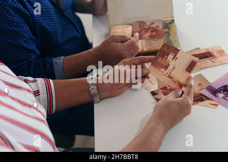 Mani di una coppia anziana sfogliando un vecchio album fotografico Foto Stock