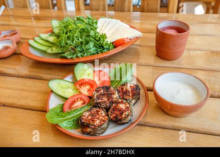Pranzo abbondante armeno. Sul tavolo c'è una dolma di kebab shish con verdure e salsa matsoni. Cucina tradizionale Foto Stock