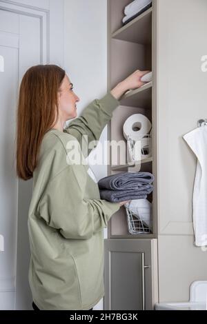 Le mani della donna mettono ordinatamente o espongono un pulito arrotolato su asciugamani bianchi fatti da cotone organico. Foto Stock