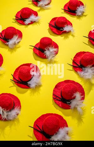Quindici cappelli di lana feltrati con una piuma su sfondo giallo Foto Stock