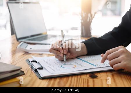 Donna d'affari che discute di grafici o grafici di analisi sul tavolo da lavoro e usando il computer portatile. Primo piano analisi femminile e concetto di strategia Foto Stock