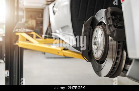 Dischi e pastiglie dei freni dei veicoli moderni Sostituzione in Auto Service Close Up autorizzato. Auto su un ascensore in manutenzione. Settore dei trasporti. Foto Stock