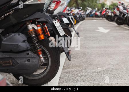 Keelung, Taiwan - 7 settembre 2018: Scooter stand parcheggiato in fila sulla strada, primo piano foto con fuoco selettivo Foto Stock