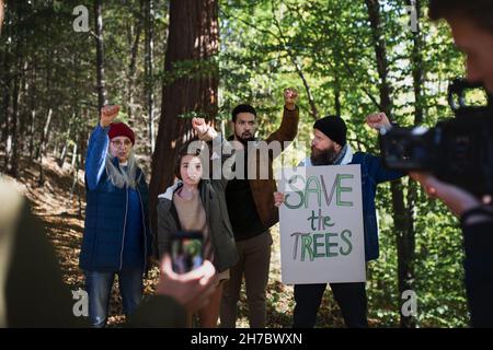 Un gruppo diversificato di attivisti ambientali con banner protestig contro la construción illegale nella foresta Foto Stock