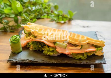 Waffle belgi con pesce e avocado sul piatto nero Foto Stock